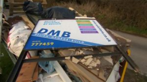 DMB Solutions (building firm) sign lying discarded on a heap of rubble