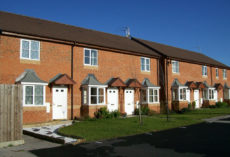 Shared Ownership Schemes A street of small, cottage-style red brick houses against a blue sky